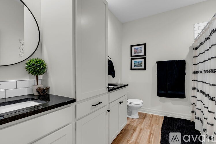 A bathroom with a black and white theme, featuring a sink, toilet, and a shower curtain.