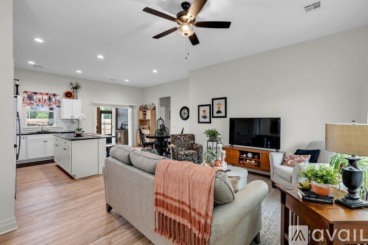 A living room with a couch, a television, and a ceiling fan.
