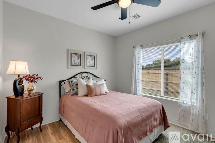 A bedroom with a bed, a nightstand with a lamp, and two pictures on the wall.