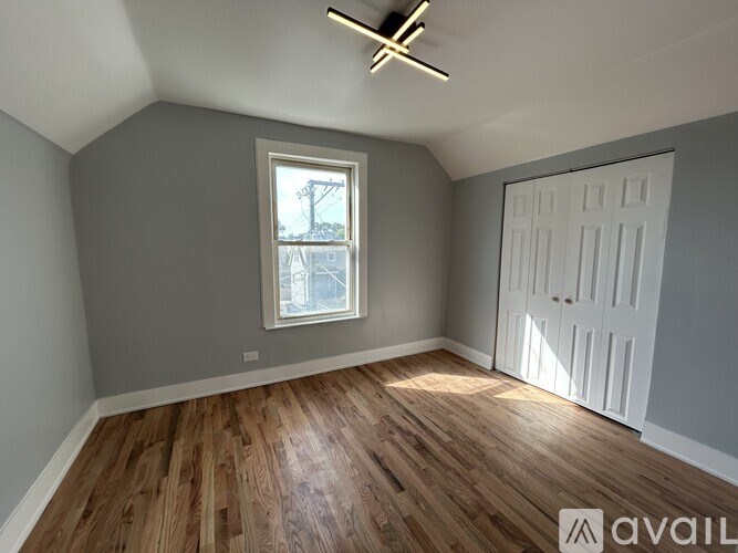 A room with wooden flooring and a window with a view of a street.