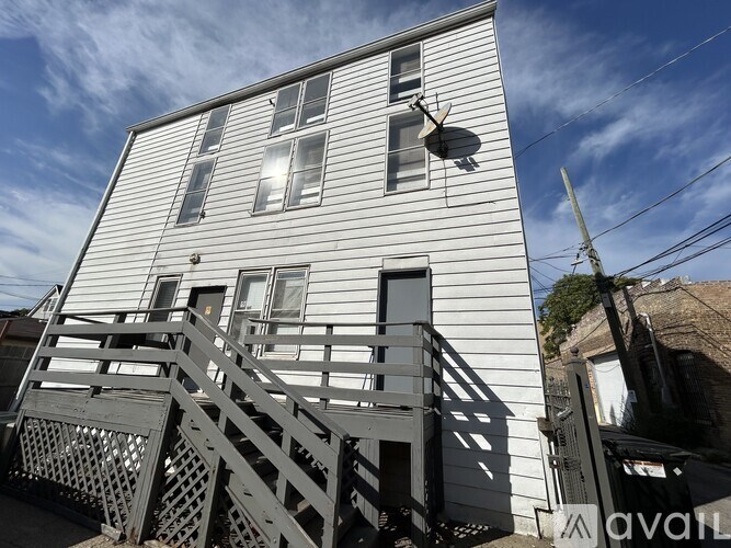 A white house with a satellite dish on the roof and a metal staircase leading to the entrance.