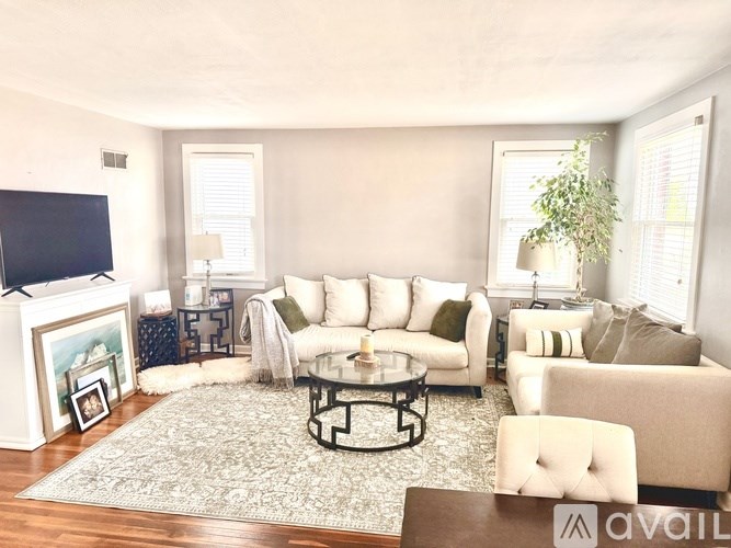 A living room with a white couch, a coffee table, and a television.