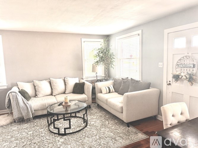 A living room with a white couch, a glass coffee table, and a plant.