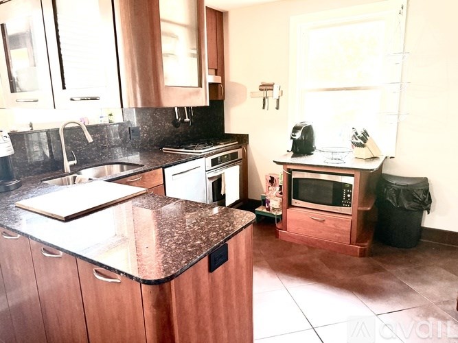 A kitchen with a black granite counter top and wooden cabinets.