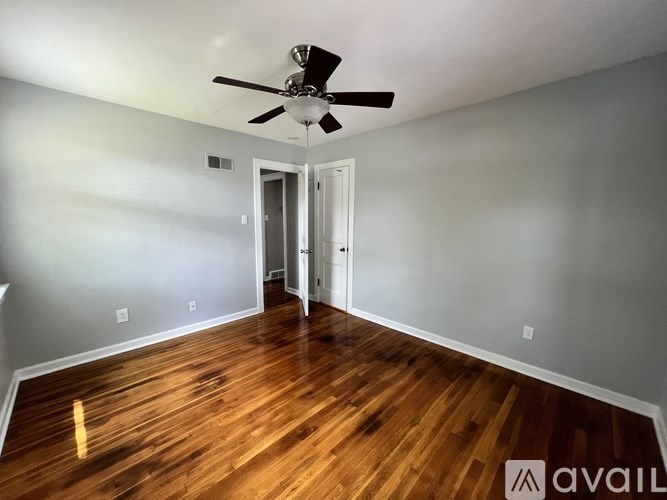 A room with a ceiling fan and wooden flooring.