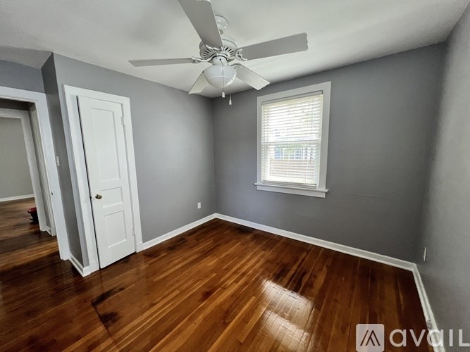 A room with a ceiling fan and a window with blinds.