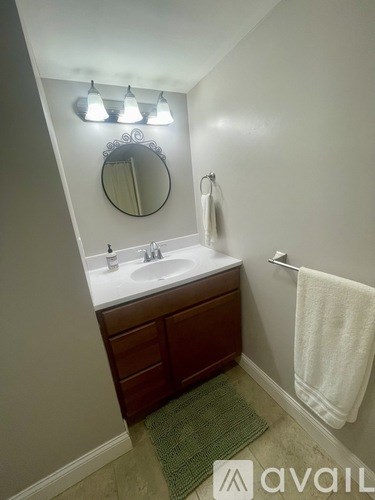 A bathroom with a sink, mirror, and towel rack.