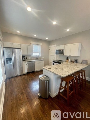 A kitchen with a white counter top and wooden floors.