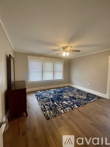 A room with a ceiling fan and a rug on the floor.
