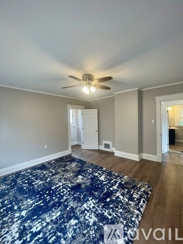 A room with a ceiling fan and a rug on the floor.