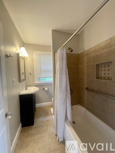 A bathroom with a white shower curtain and a black cabinet.
