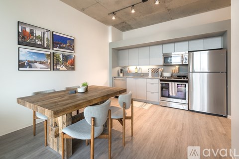 A kitchen with a table and chairs in the foreground and a fridge, microwave, and oven in the background.