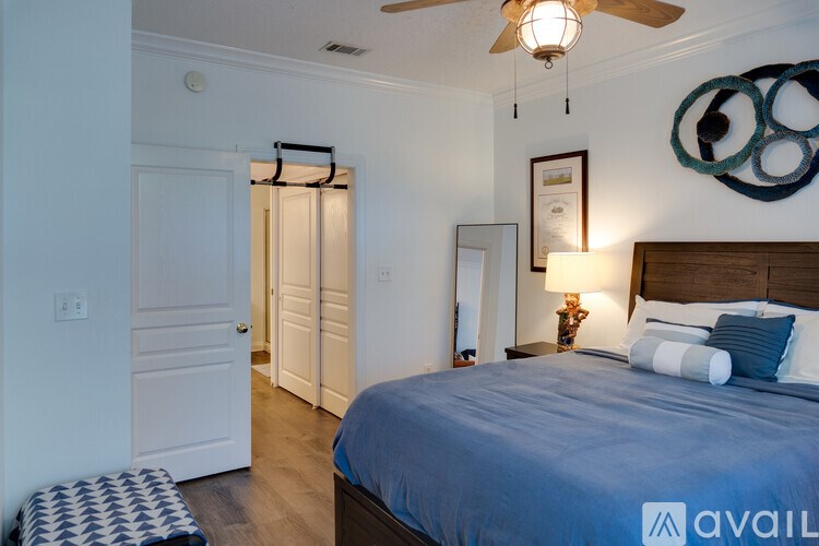 A bedroom with a bed, a ceiling fan, and a mirror.