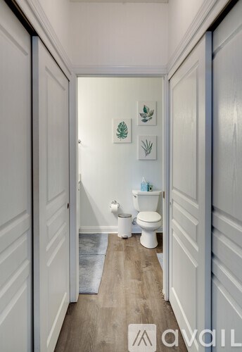 A narrow hallway with a toilet and a toilet paper roll on the floor.