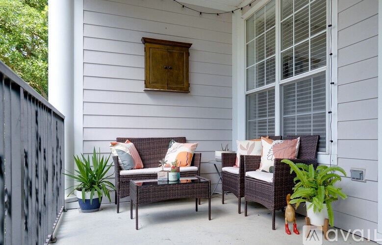 A patio with a sofa, chairs, and potted plants.