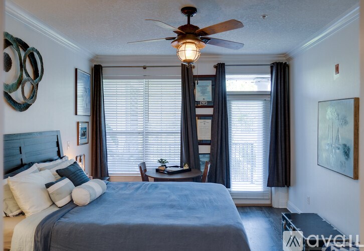 A bedroom with a bed, a ceiling fan, and a window with curtains.