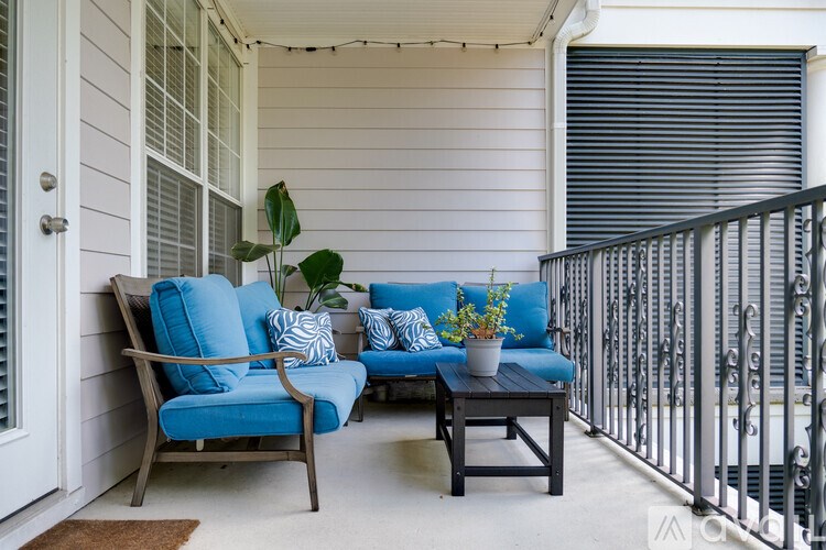 A blue couch and chair are on a porch with a table between them.
