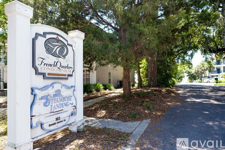 A sign for French Owl Condos stands in front of a tree.