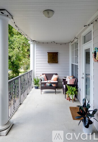 A white porch with a table and chairs.