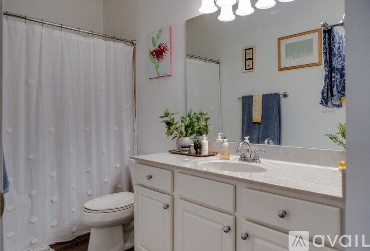 A white bathroom with a toilet, sink, and shower curtain.