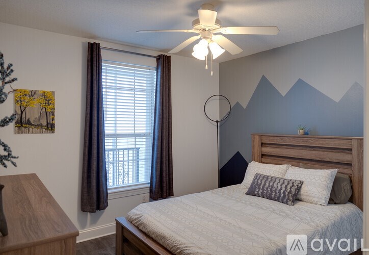 A bedroom with a bed, a ceiling fan, and a wall mural.