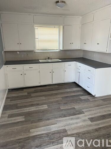 A kitchen with white cabinets and a wooden floor.