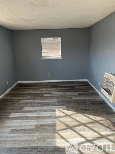 A room with wooden flooring and a window.