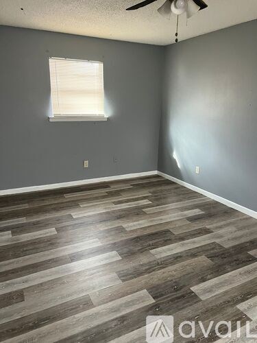 A room with wooden flooring and a window with blinds.