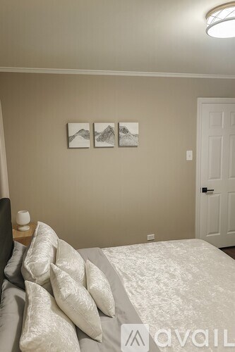 A bedroom with a bed, pillows, and pictures on the wall.