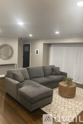 A grey sofa with a wicker side table and a round mirror on the wall.
