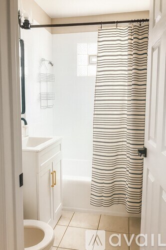 A bathroom with a toilet, sink, and shower curtain.