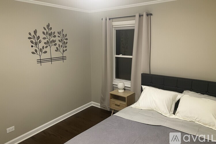 A bedroom with a bed, nightstand, and a wall decal of a plant.