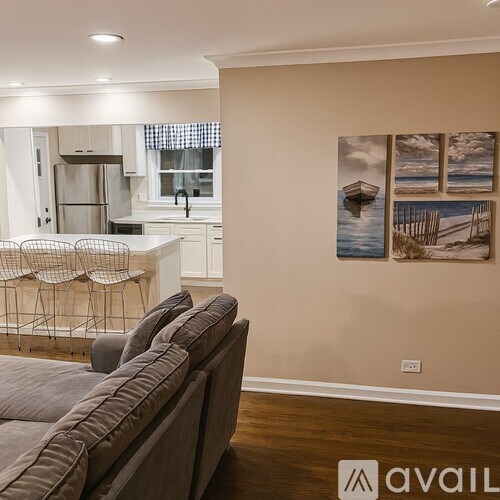 A living room with a grey couch and a painting of a boat on the wall.