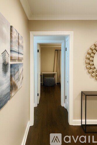 A hallway with a painting on the wall and a round mirror on the wall.