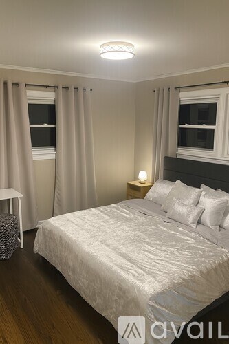 A bedroom with a large bed and a window with curtains.