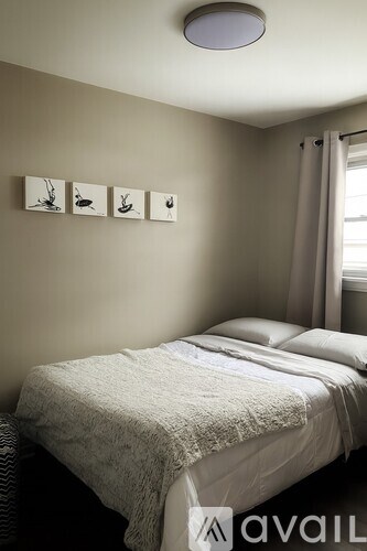 A bedroom with a bed, pillows, a blanket, and pictures on the wall.