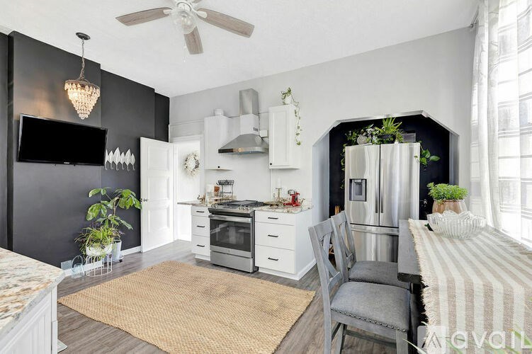 A modern kitchen with a black wall and white cabinets.