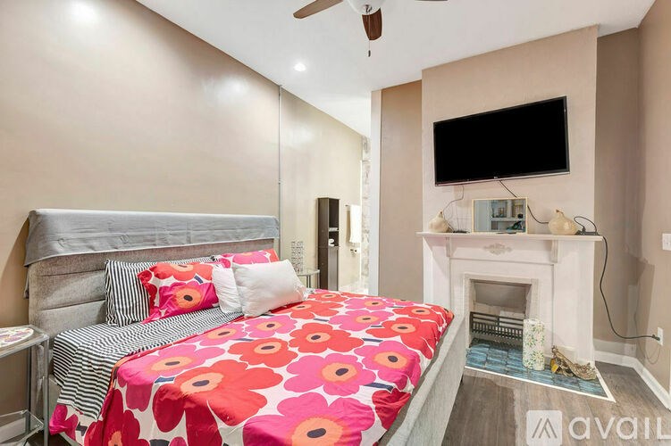 A bedroom with a bed, a fireplace, and a television.