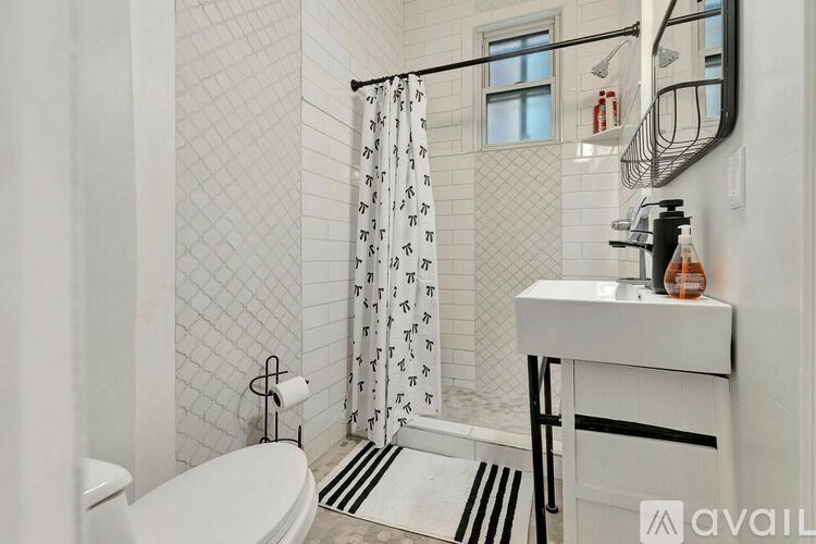 A bathroom with a white toilet, a white sink, and a shower curtain with black and white designs.