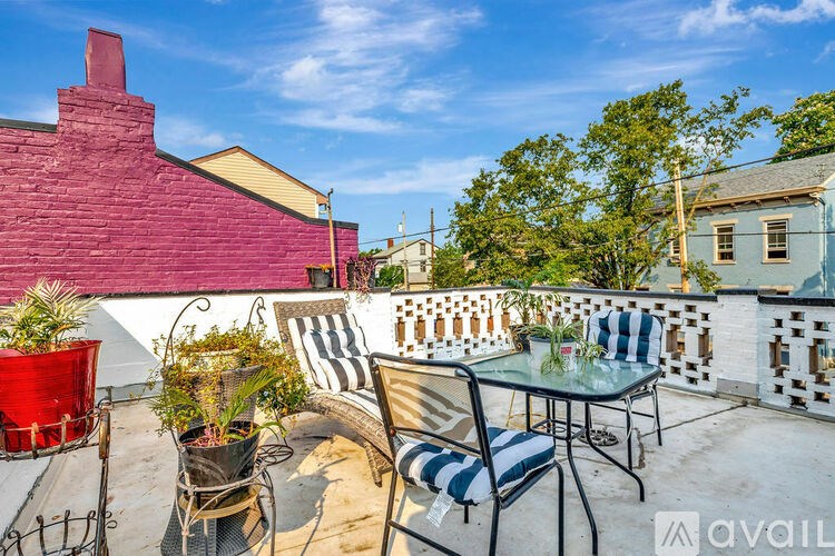 A balcony with a table, chairs, and plants.