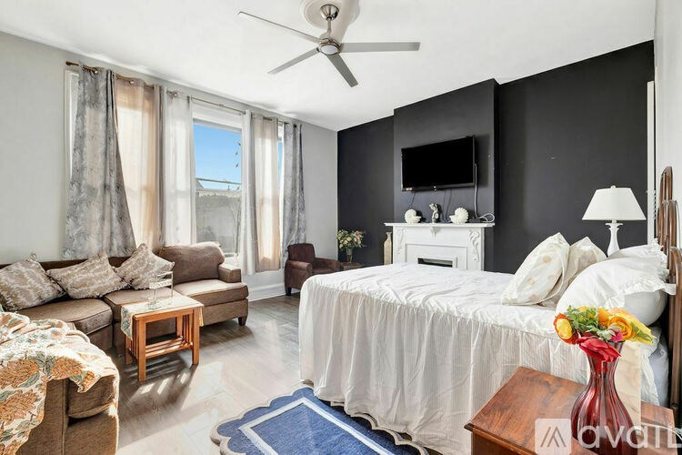 A bedroom with a bed, a couch, a chair, and a television.