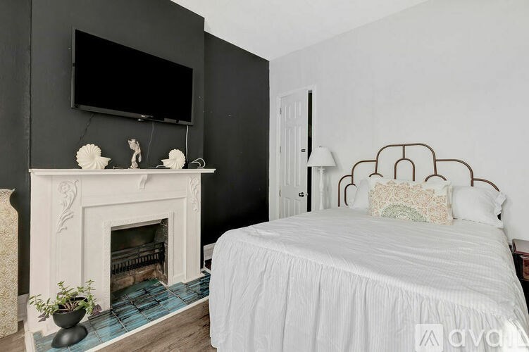 A bedroom with a bed, a fireplace, and a television mounted on the wall.