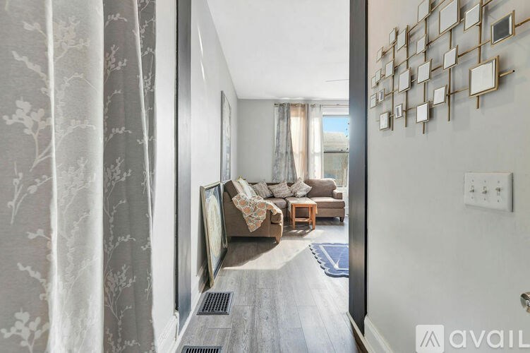 A hallway with a grey carpet and a wall with a mirror and a picture frame.