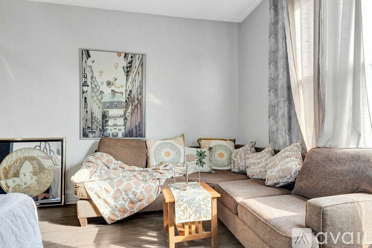 A living room with a couch, a chair, a table, and a painting on the wall.