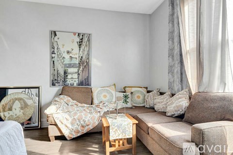 A living room with a couch, a chair, a table, and a painting on the wall.