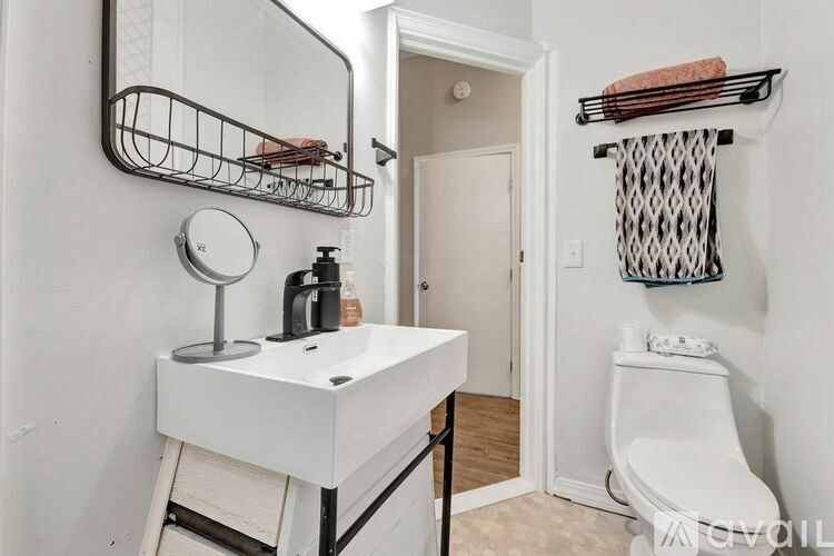 A white bathroom vanity with a mirror and a towel rack.