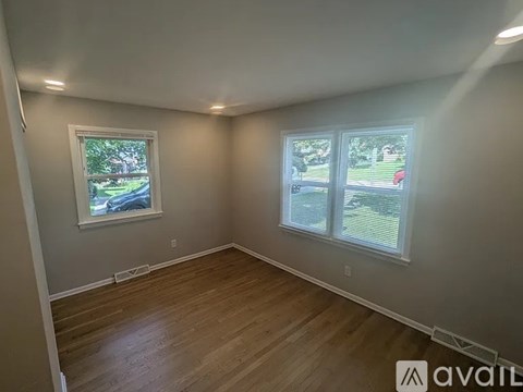 A room with wooden floors and two windows.