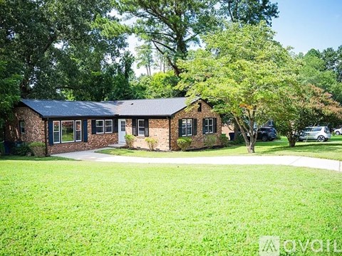 A house with a green lawn and trees in the background.