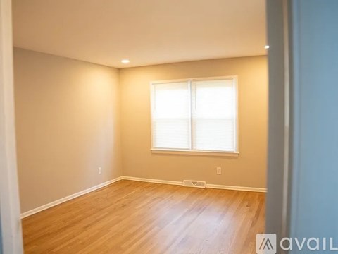 A room with wooden flooring and a window with blinds.