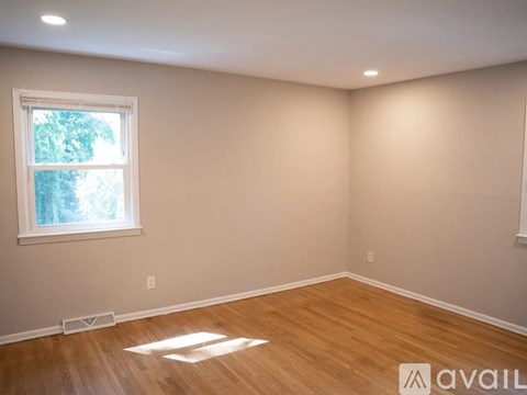 A room with wooden flooring and a window letting in natural light.